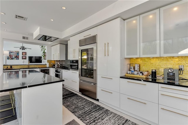 4809 Neyrey Dr, Metairie, LA 70002 - kitchen featuring built in refrigerator, dark countertops, backsplash, white cabinets, and a ceiling fan