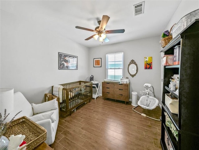 2738 Cleveland Ave, New Orleans, LA 70119 - bedroom with baseboards, visible vents, a ceiling fan, wood finished floors, and a nursery area