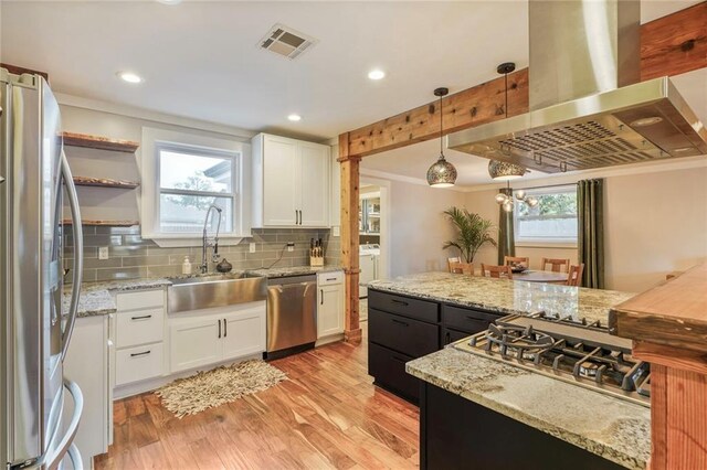 kitchen with white cabinets, island exhaust hood, a sink, visible vents, and appliances with stainless steel finishes