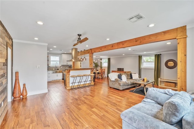 living room featuring recessed lighting, light wood finished floors, visible vents, a ceiling fan, and ornamental molding