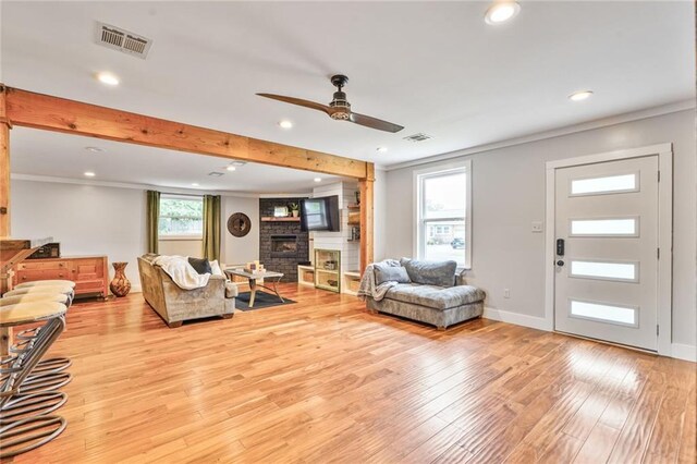 living area with a stone fireplace, visible vents, and light wood-style flooring