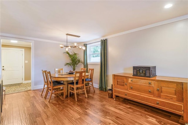 dining room with light wood-style floors, a notable chandelier, baseboards, and ornamental molding