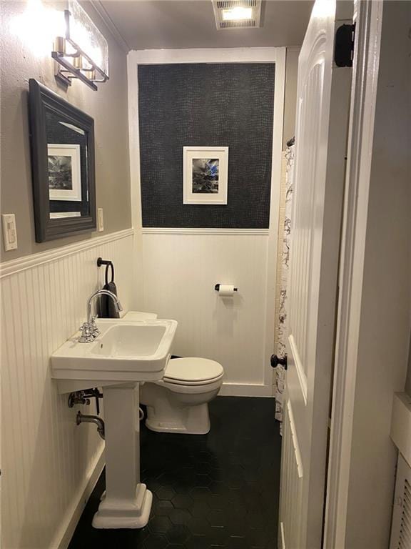 full bathroom featuring a wainscoted wall, visible vents, and toilet