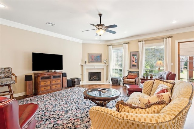 living area with crown molding, a wealth of natural light, wood finished floors, and a ceiling fan