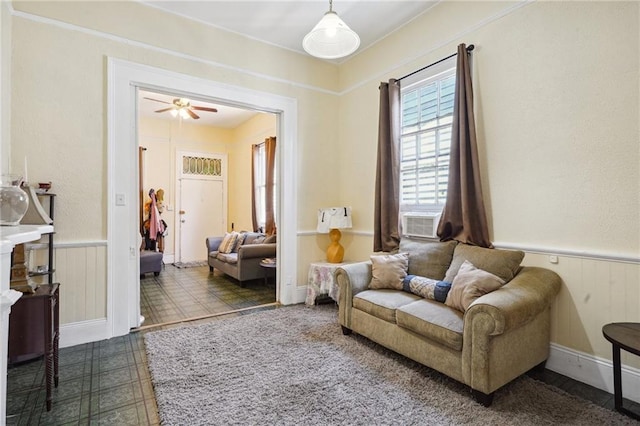 living area featuring a wainscoted wall, cooling unit, and ceiling fan