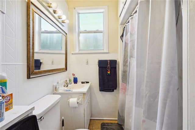 bathroom with plenty of natural light, tile walls, vanity, and toilet