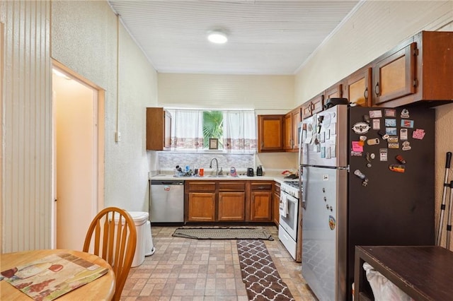 kitchen featuring light countertops, ornamental molding, a sink, brown cabinetry, and appliances with stainless steel finishes