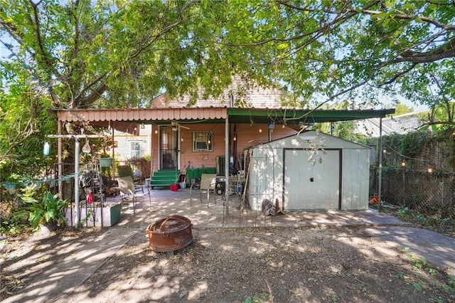 rear view of house featuring a patio area, a storage shed, a fire pit, fence, and an outbuilding