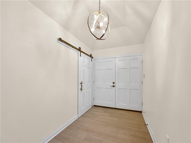 foyer entrance with a chandelier, light wood-style floors, a barn door, and baseboards