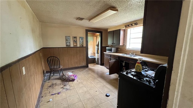 39202 Pine St, Pearl River, LA 70452 - kitchen with a wainscoted wall, visible vents, a sink, black gas stove, and a textured ceiling