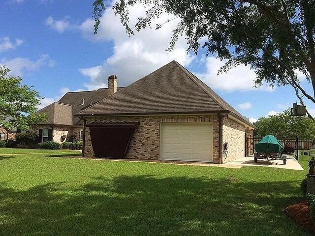 view of side of home featuring a lawn, brick siding, and a garage
