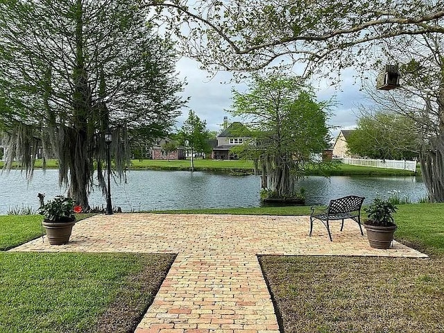 surrounding community with a water view and a yard