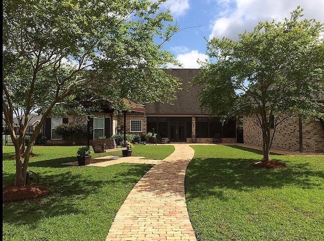 view of front facade with brick siding, french doors, and a front lawn