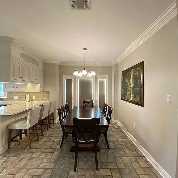 dining area featuring visible vents, ornamental molding, baseboards, and a notable chandelier