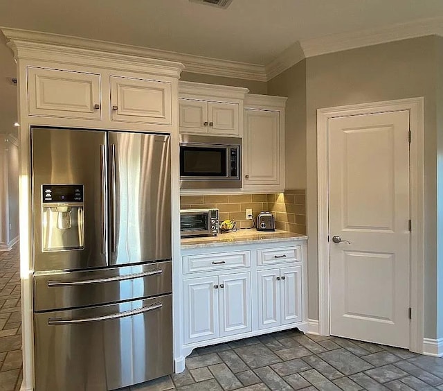 kitchen with brick floor, a toaster, appliances with stainless steel finishes, light countertops, and ornamental molding