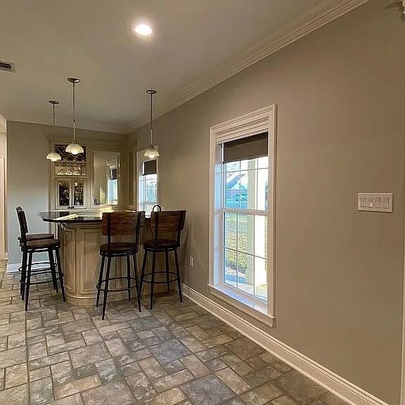 interior space featuring crown molding, brick floor, pendant lighting, baseboards, and recessed lighting