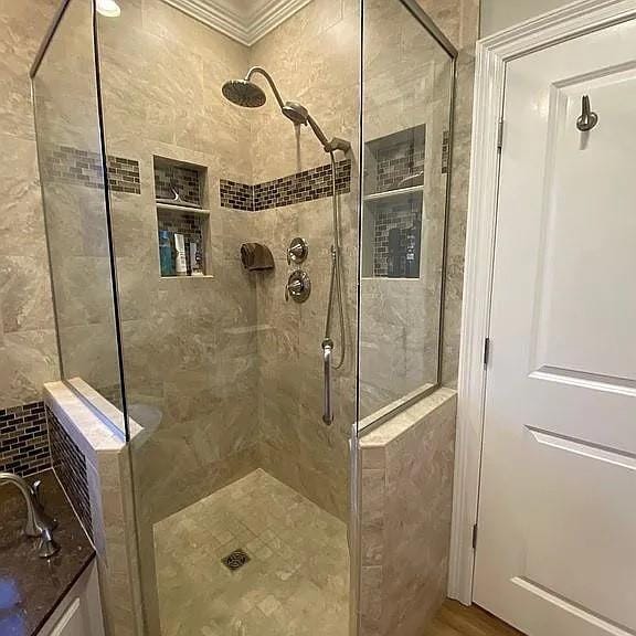 full bathroom with a shower stall and ornamental molding