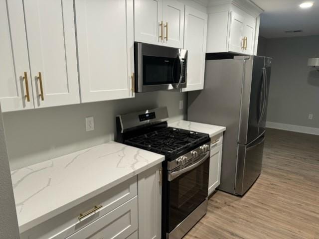 42 Boimare Ave, Kenner, LA 70065 - kitchen with appliances with stainless steel finishes, light wood-style flooring, white cabinetry, and light stone countertops