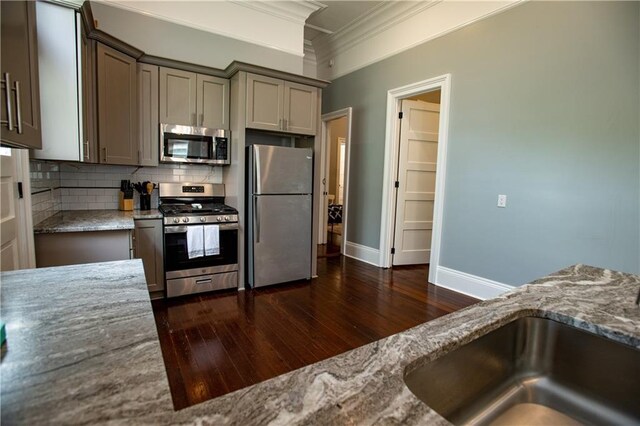 1529 Saint Philip St, New Orleans, LA 70116 - kitchen with appliances with stainless steel finishes, crown molding, dark wood-style floors, tasteful backsplash, and a sink