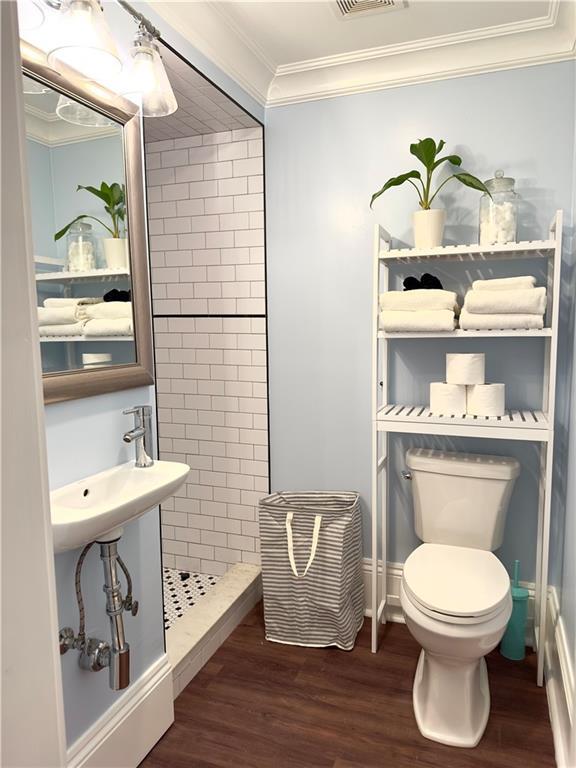 1529 Saint Philip St, New Orleans, LA 70116 - full bathroom featuring wood finished floors, crown molding, toilet, and a stall shower