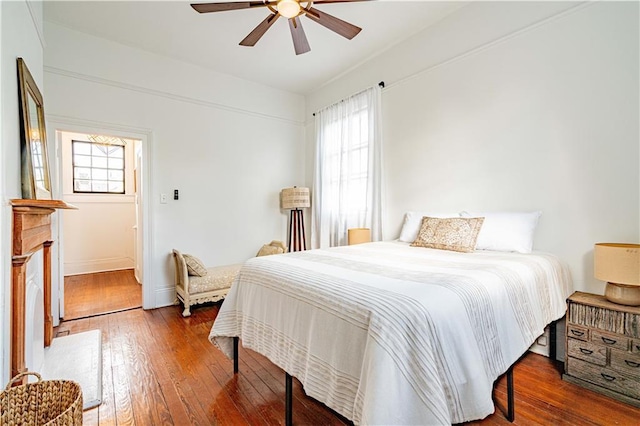 bedroom featuring hardwood / wood-style flooring, baseboards, ceiling fan, and multiple windows