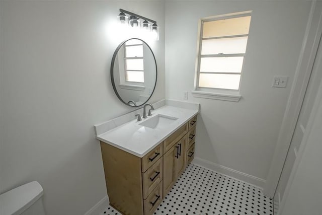 bathroom featuring toilet, baseboards, and vanity