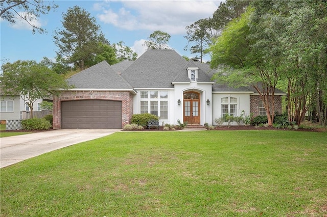 265 Remington Dr, Mandeville, LA 70448 - french country inspired facade with driveway, french doors, a front yard, a garage, and roof with shingles