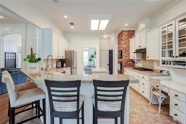 265 Remington Dr, Mandeville, LA 70448 - kitchen with crown molding, glass insert cabinets, a peninsula, appliances with stainless steel finishes, and visible vents