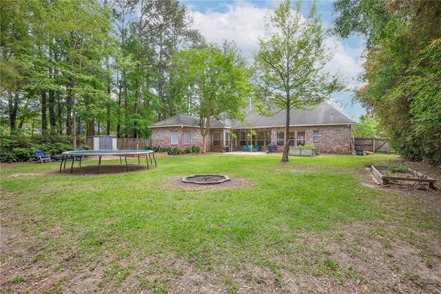 265 Remington Dr, Mandeville, LA 70448 - view of yard featuring fence, a storage shed, an outdoor structure, a fire pit, and a trampoline