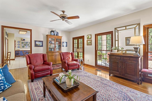 living area with a ceiling fan, visible vents, light wood-style flooring, and baseboards