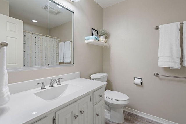 bathroom featuring visible vents, baseboards, toilet, wood finished floors, and vanity