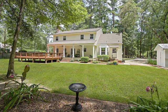 rear view of house featuring a chimney, a shingled roof, a ceiling fan, and a yard