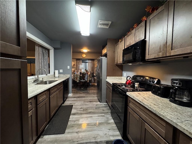 kitchen featuring light wood-style flooring, a sink, visible vents, dark brown cabinets, and black appliances