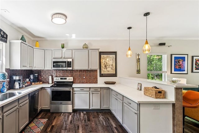 kitchen featuring a kitchen breakfast bar, light countertops, backsplash, a peninsula, and appliances with stainless steel finishes