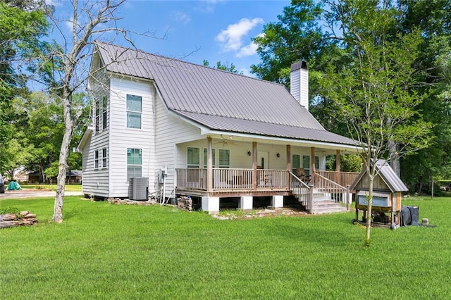 back of property featuring central air condition unit, a chimney, a porch, a yard, and metal roof