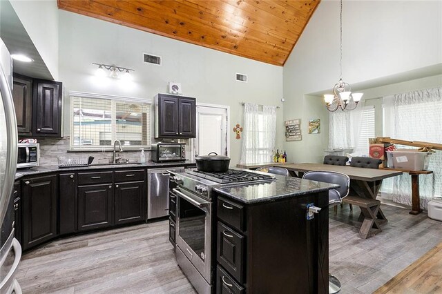 kitchen with stainless steel appliances, visible vents, an inviting chandelier, dark cabinets, and high vaulted ceiling