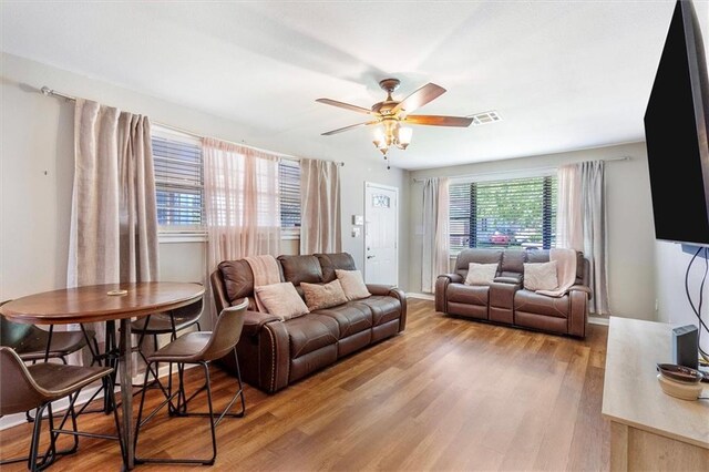 living area featuring wood finished floors, a healthy amount of sunlight, ceiling fan, and visible vents