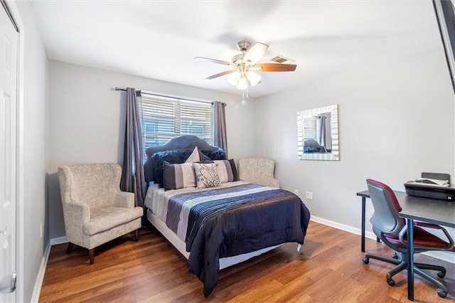 bedroom featuring baseboards, a ceiling fan, wood finished floors, and visible vents