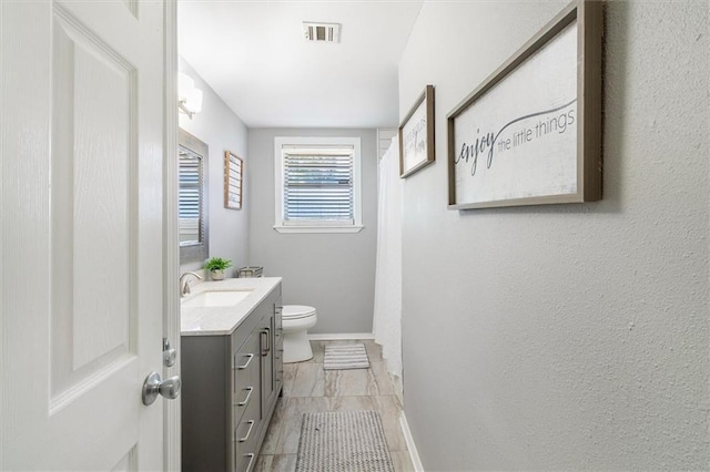 bathroom with vanity, curtained shower, baseboards, toilet, and visible vents