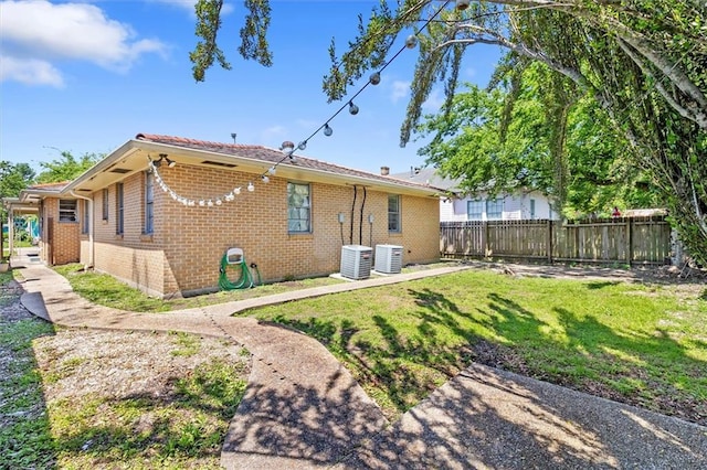 rear view of property featuring fence, a lawn, and brick siding