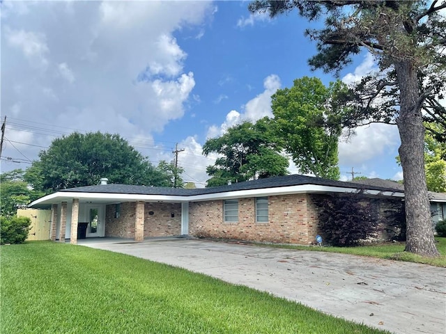 rear view of property featuring driveway, a yard, a carport, and brick siding