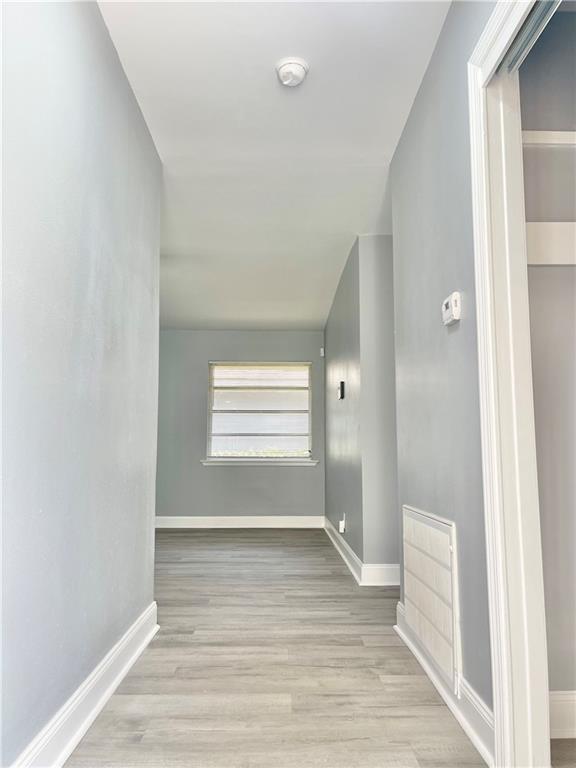 corridor featuring baseboards and wood finished floors