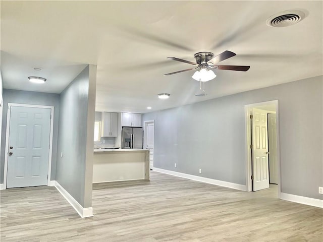 unfurnished living room with visible vents, ceiling fan, light wood-style flooring, and baseboards