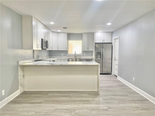 kitchen featuring appliances with stainless steel finishes, a peninsula, recessed lighting, and a sink