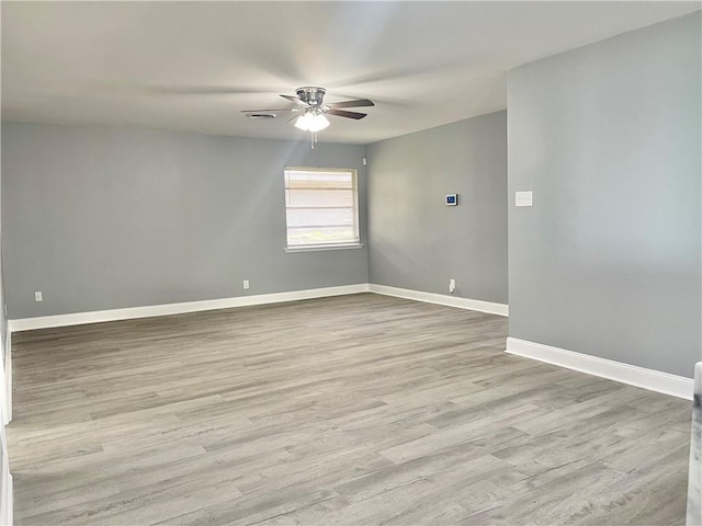 spare room with wood finished floors, ceiling fan, and baseboards
