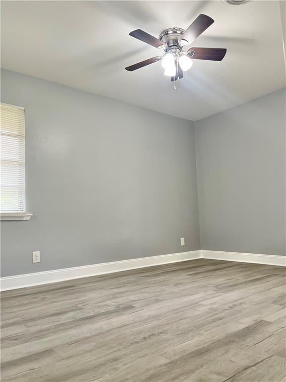 empty room with wood finished floors, ceiling fan, and baseboards