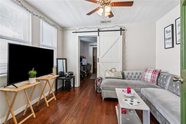 living room featuring dark wood-style floors, a barn door, visible vents, baseboards, and ceiling fan