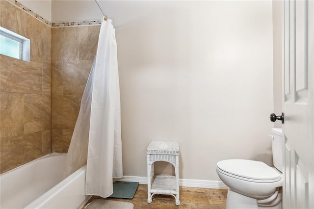 full bath with baseboards, wood finished floors, shower / bathtub combination with curtain, and toilet