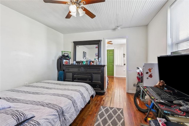 bedroom with a ceiling fan, baseboards, and wood-type flooring