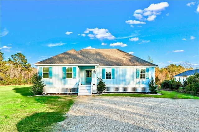 view of front facade featuring a front lawn, roof with shingles, a porch, and board and batten siding